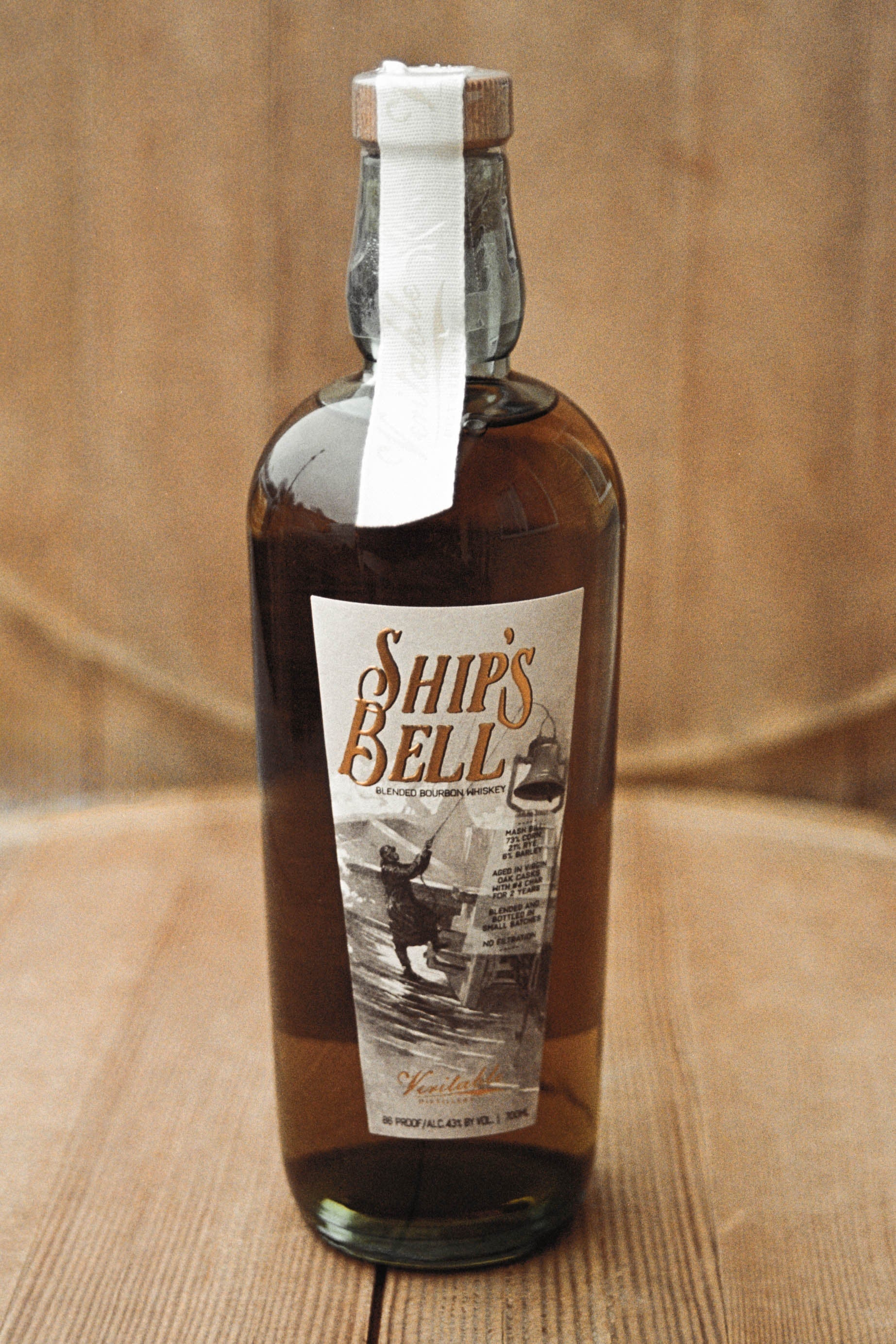 Image of Ship's Bell Bourbon bottle on a wood background.
