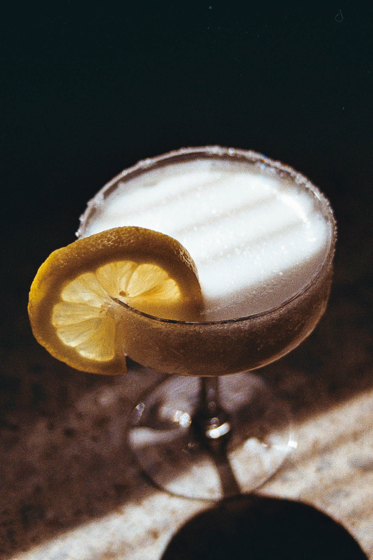 Limoncello cocktail in coupe glass with sugar rim and a lemon wheel. Made with Limoncello, cream, lemon juice and bitters.