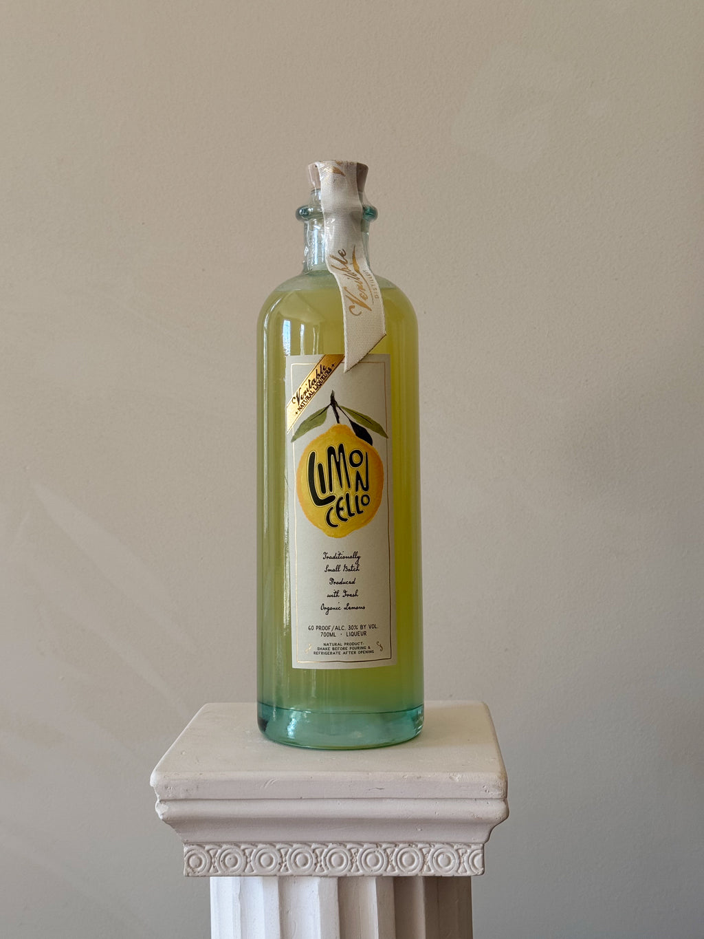 Bottle of 'Veritable Limoncello' on a white pedestal against a beige background