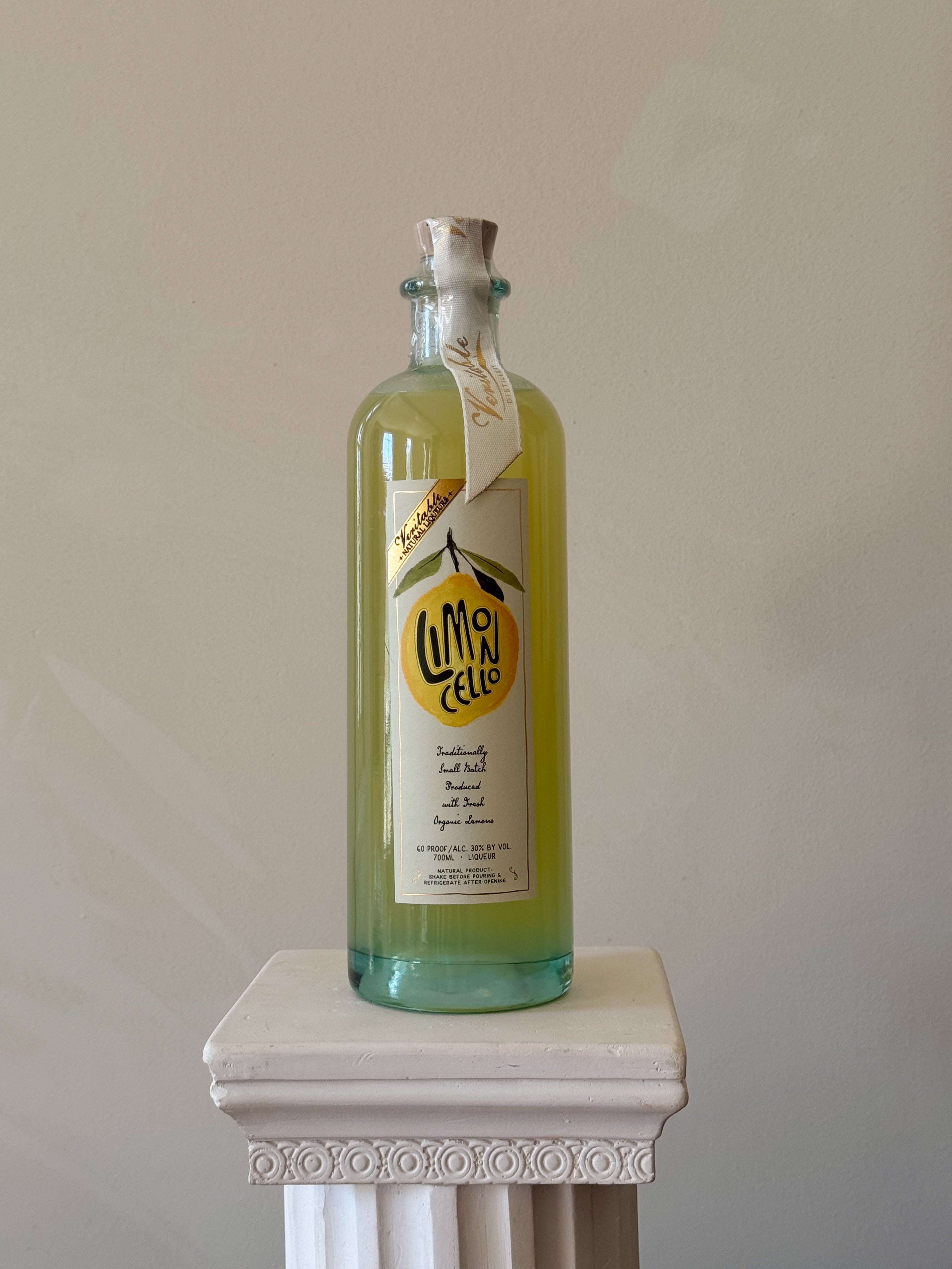 Bottle of 'Veritable Limoncello' on a white pedestal against a beige background