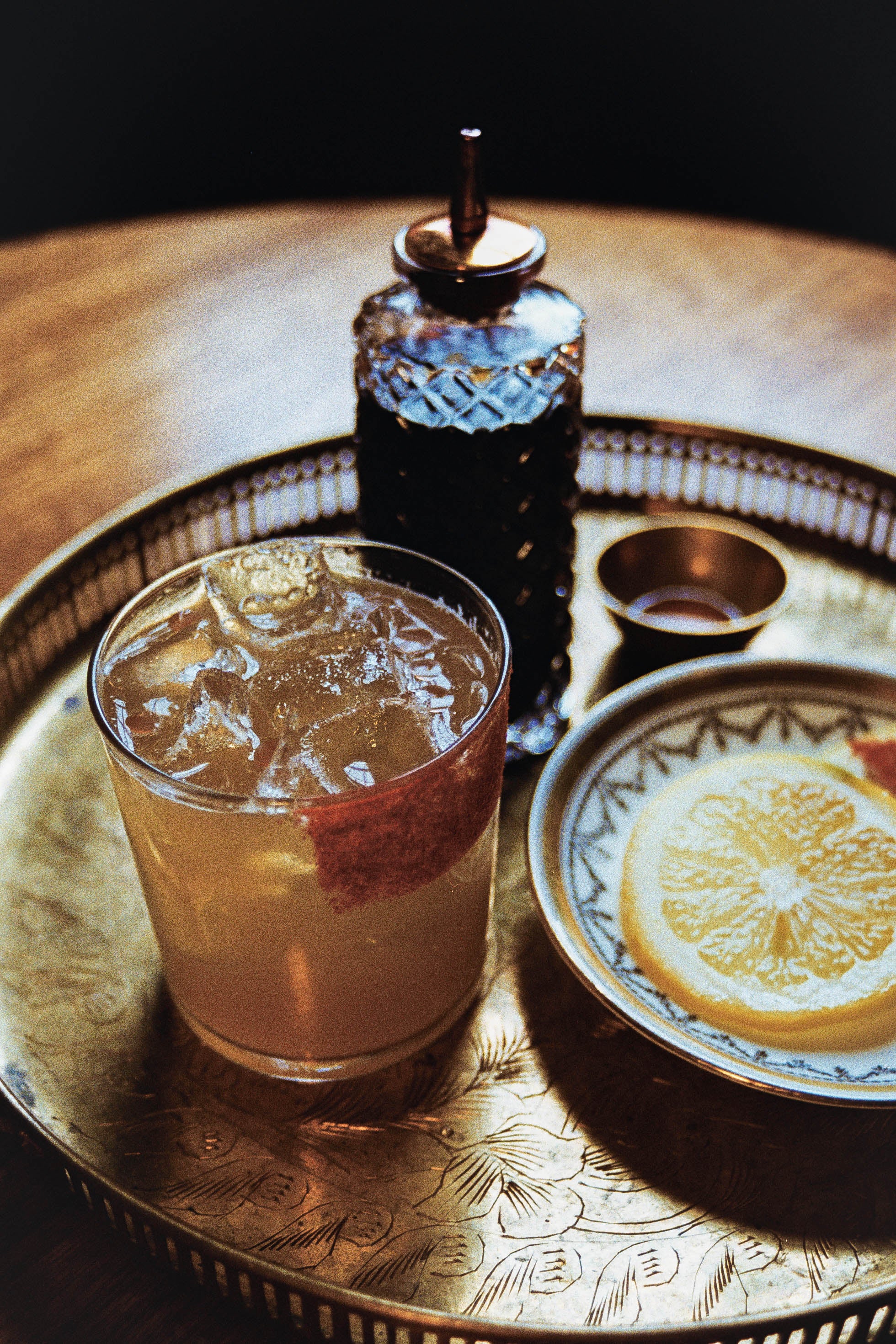 Image of Wraith in the Goldmine cocktail in a rocks glass. Bourbon, lemon and honey with chili oil a paprika rim.